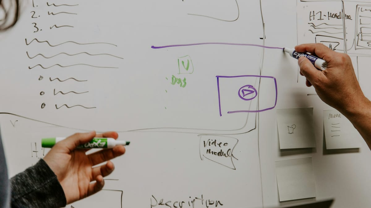 Two people sketching a plan on a whiteboard
