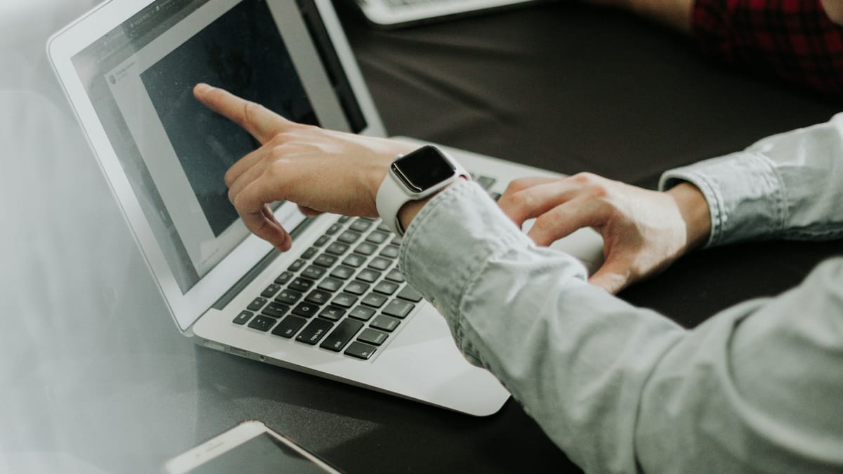 Two people working at a table with laptops