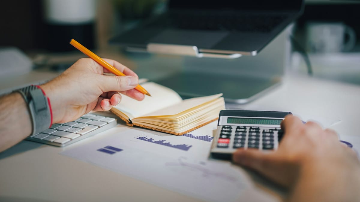 Person working through numbers with a calculator and notebook
