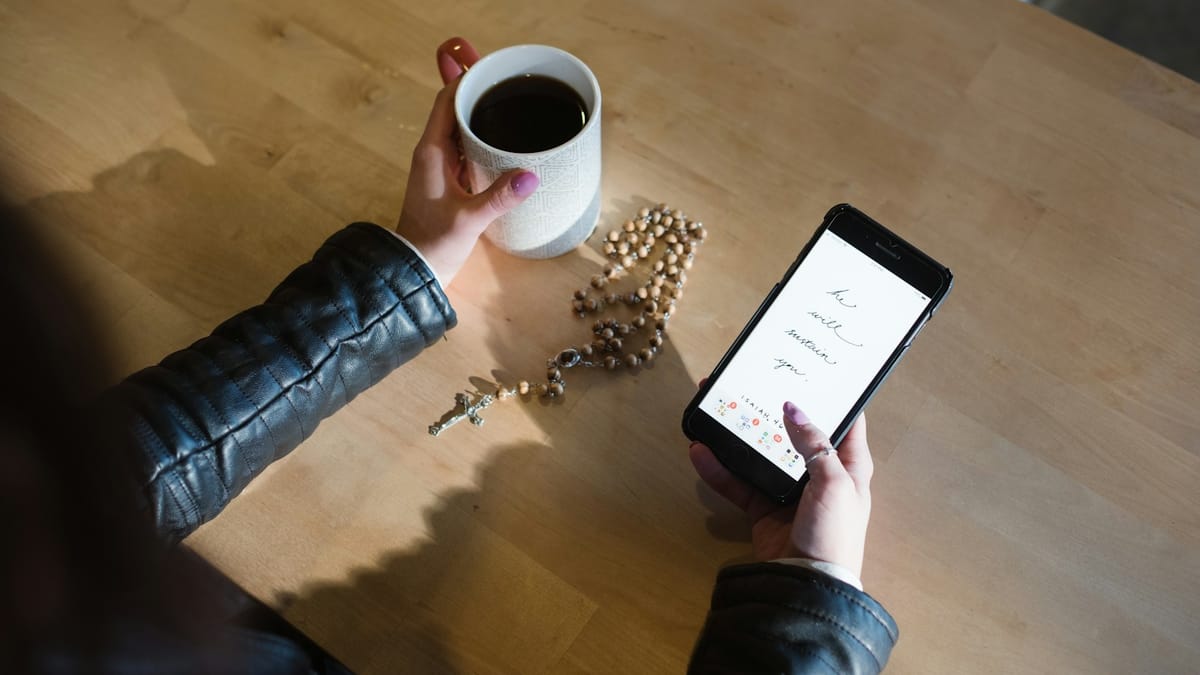 Person checking a message on their phone over morning coffee