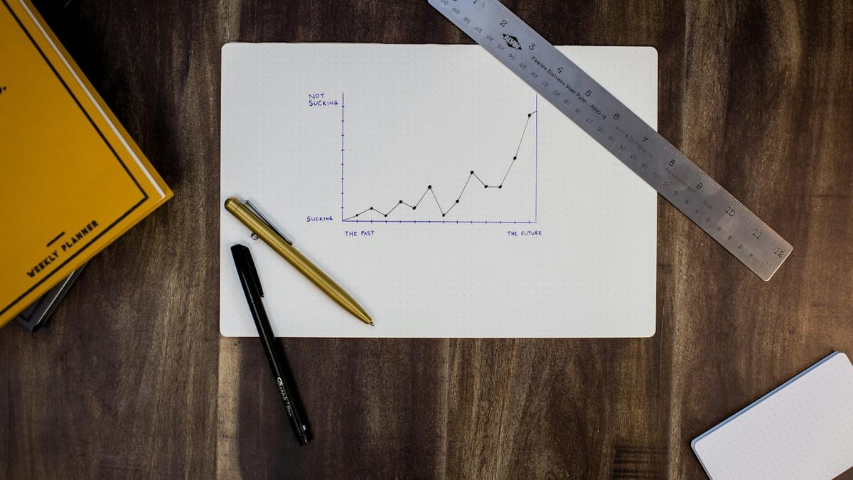 Hand-drawn line graph on paper with a ruler and pens